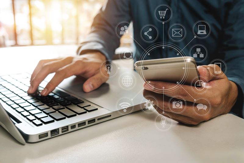 Man on laptop holding cell phone